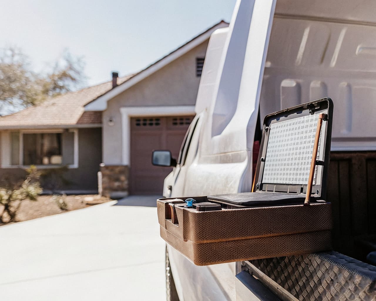 Home services van with an open toolbox and a mounted tablet showing a calendar interface, parked in a suburban driveway